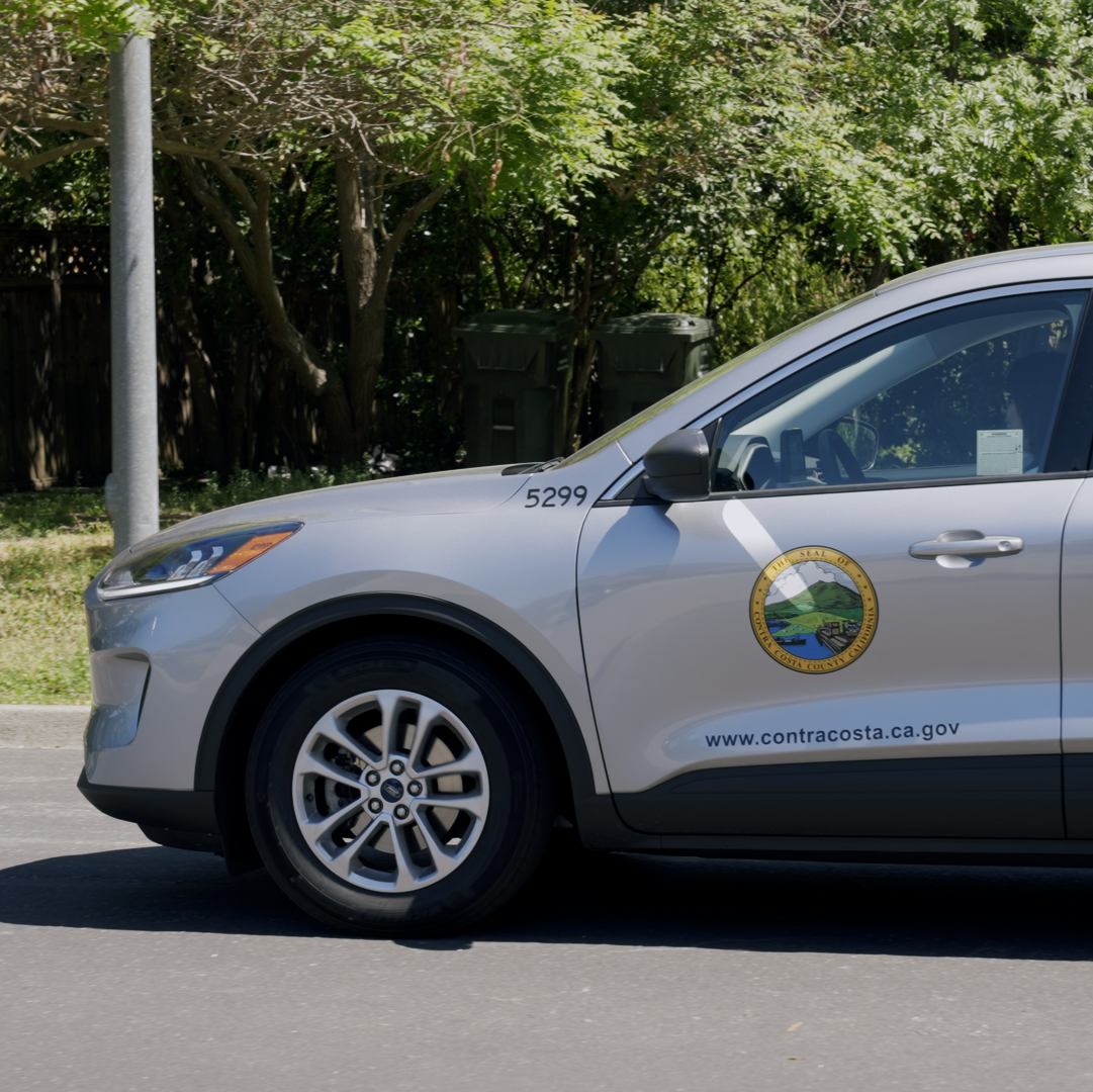 photo of a silver car bearing the seal of the crisis care mobile unit project and the address of the Contra Costa county website.